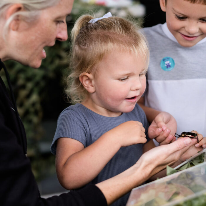 A little girl smiles while an adult woman reads from a book