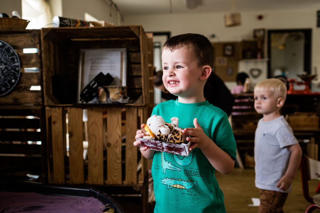 A boy holds up a box that he has made into a bed for his toy mouse