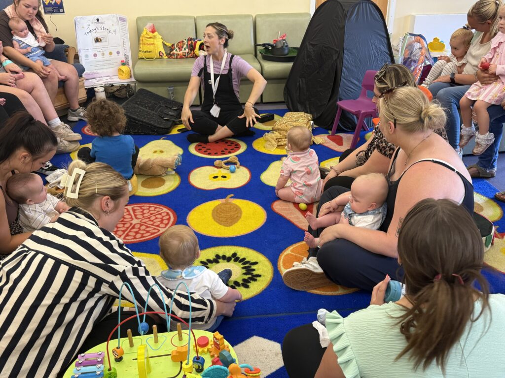 Parents and children gather on the floor to listen to a storyteller